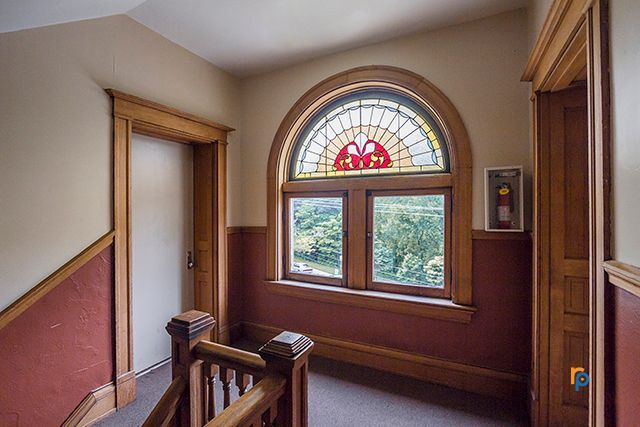 A hallway with stairs and a stained glass window.