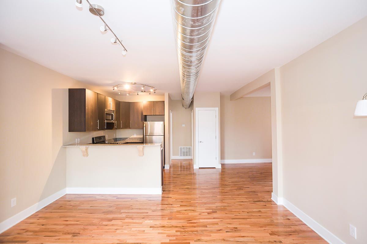 An empty apartment with hardwood floors and a kitchen