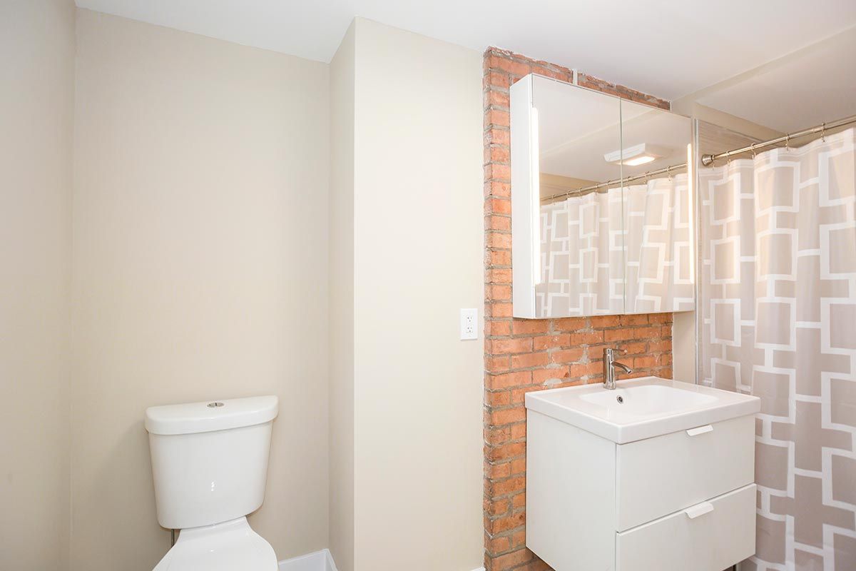 A bathroom with a toilet , sink , mirror and shower curtain.