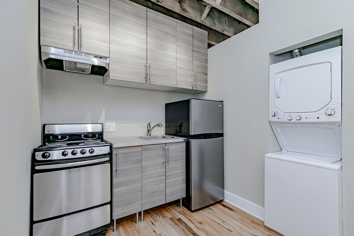 A kitchen with a refrigerator , stove , sink , and washer and dryer.