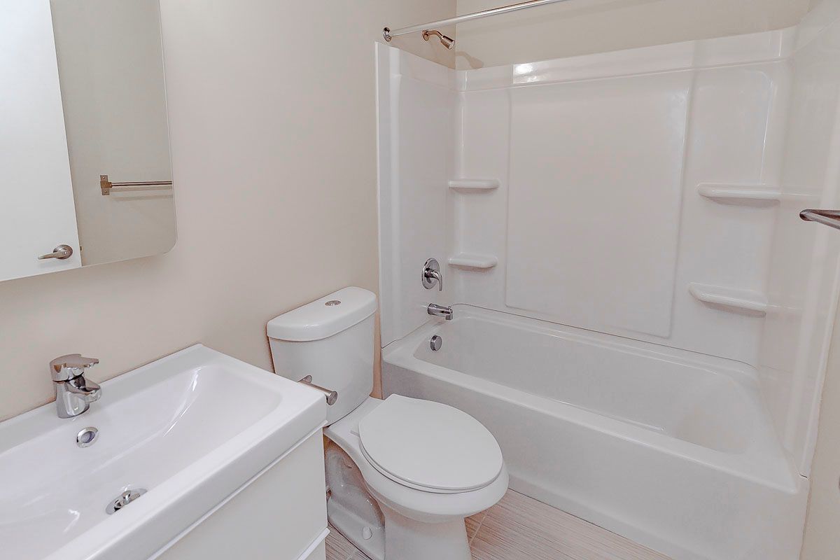 A bathroom with a toilet , sink and bathtub.