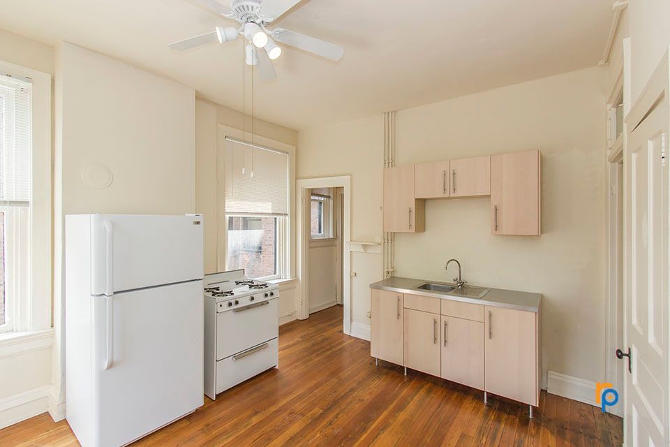 A kitchen with a refrigerator , stove , sink and ceiling fan.