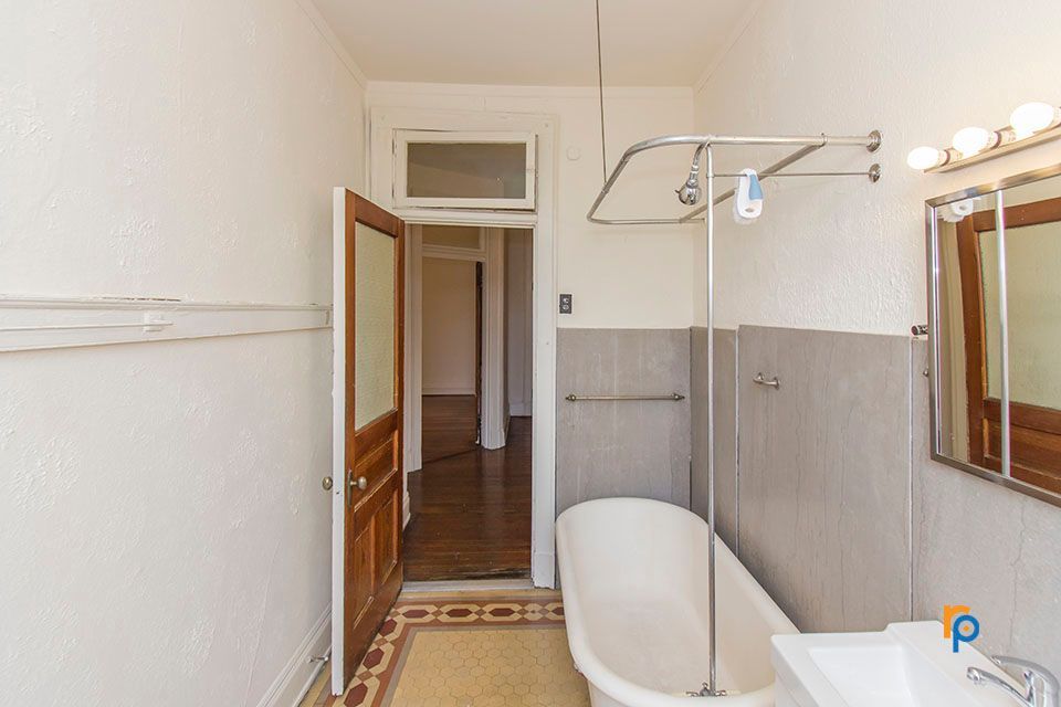 A bathroom with a bathtub , sink and mirror.