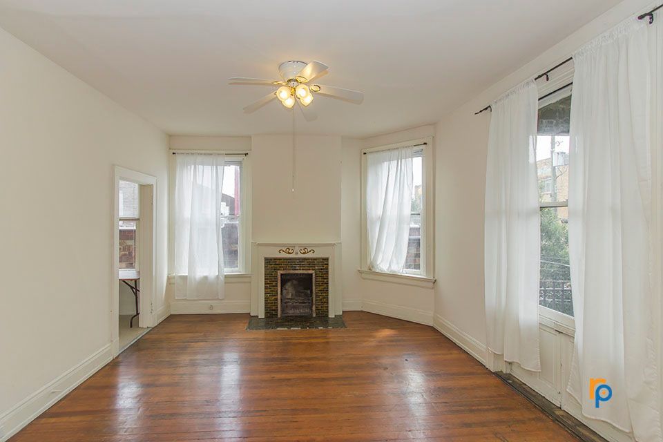 An empty living room with hardwood floors and a fireplace.
