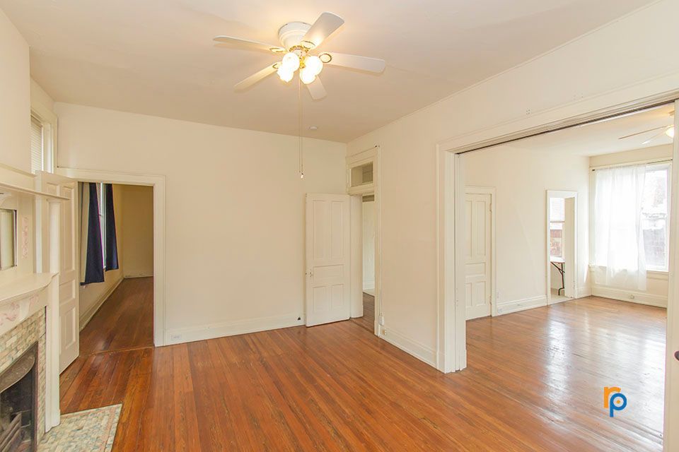 An empty living room with hardwood floors and a ceiling fan.