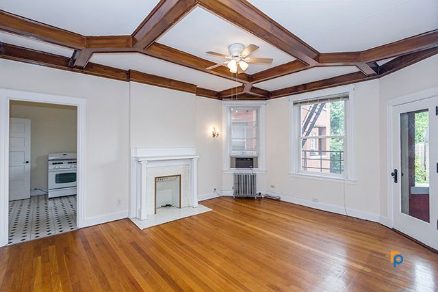 An empty living room with a fireplace and a ceiling fan