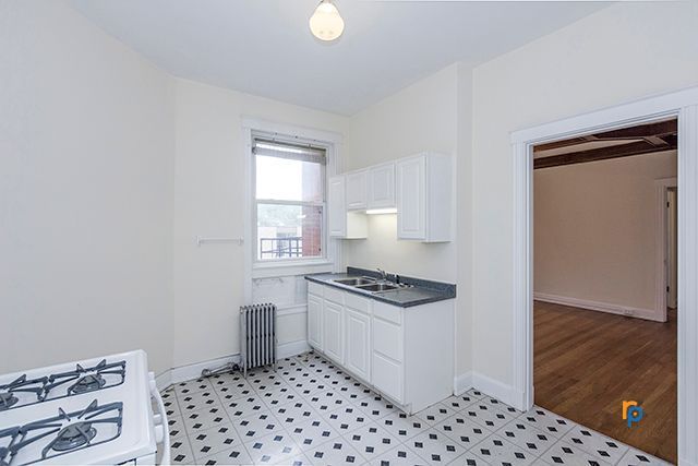 An empty kitchen with a stove , sink , and cabinets.