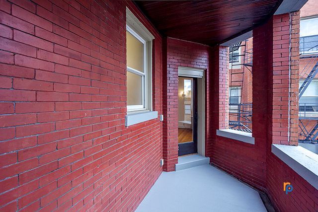 A red brick building with a porch and a window.