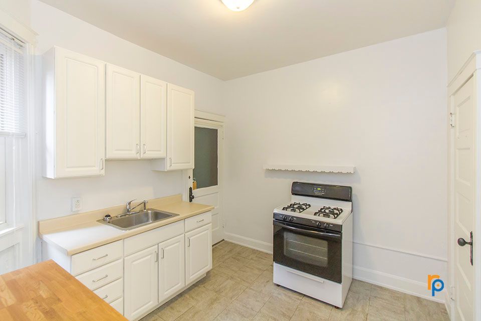 A kitchen with white cabinets , a stove and a sink.
