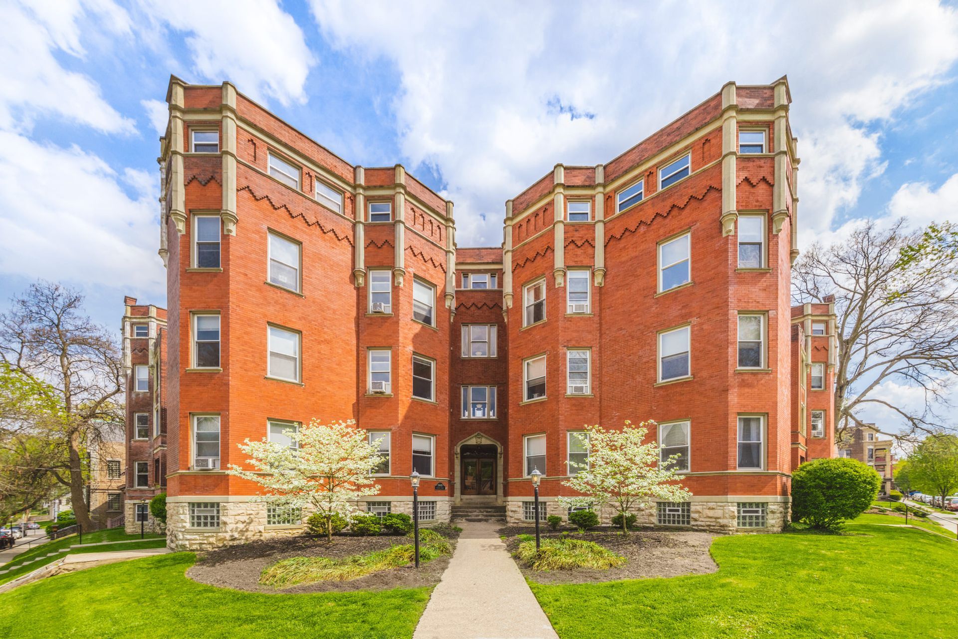 A large red brick apartment building with a walkway leading to it.