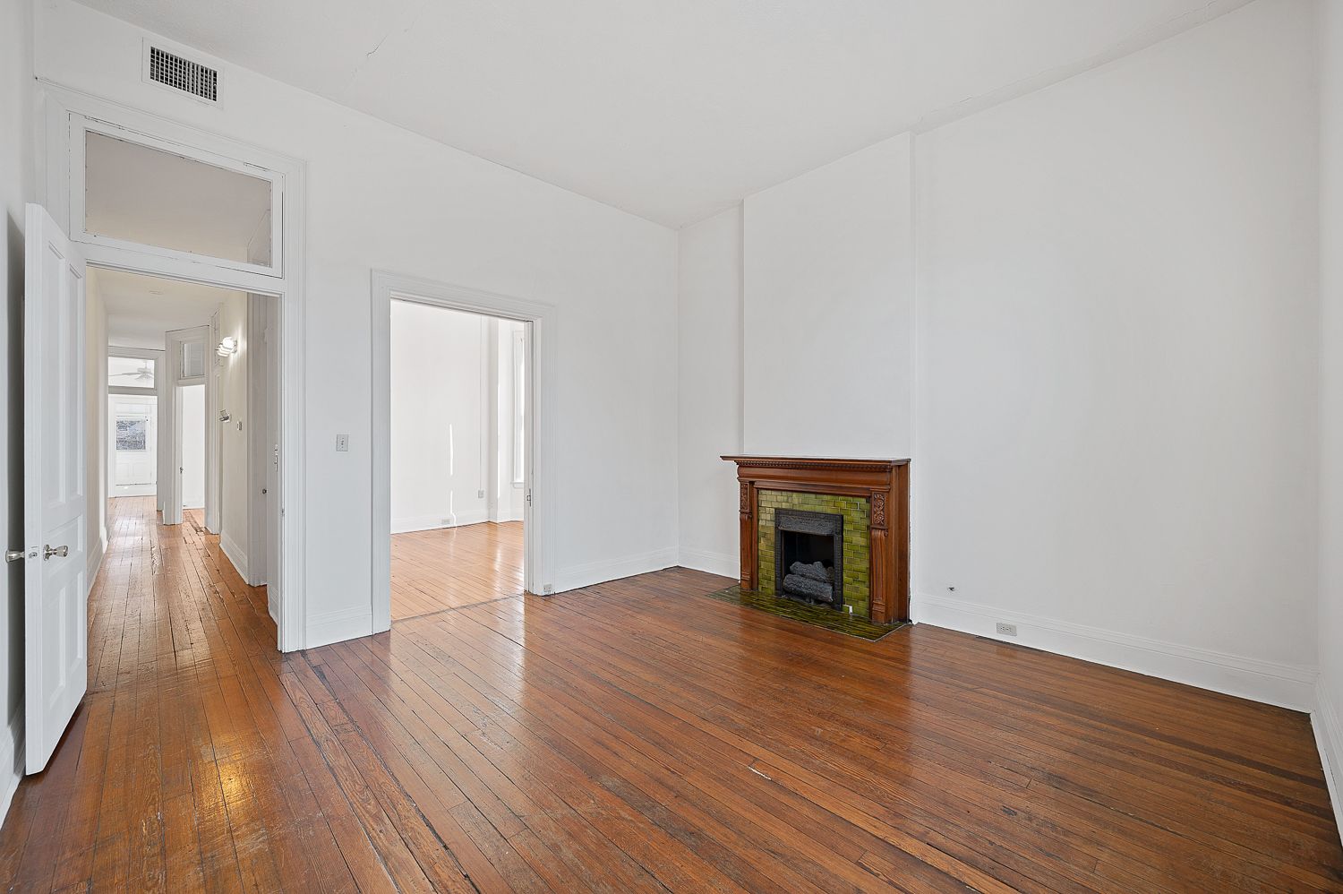 An empty living room with hardwood floors and a fireplace.