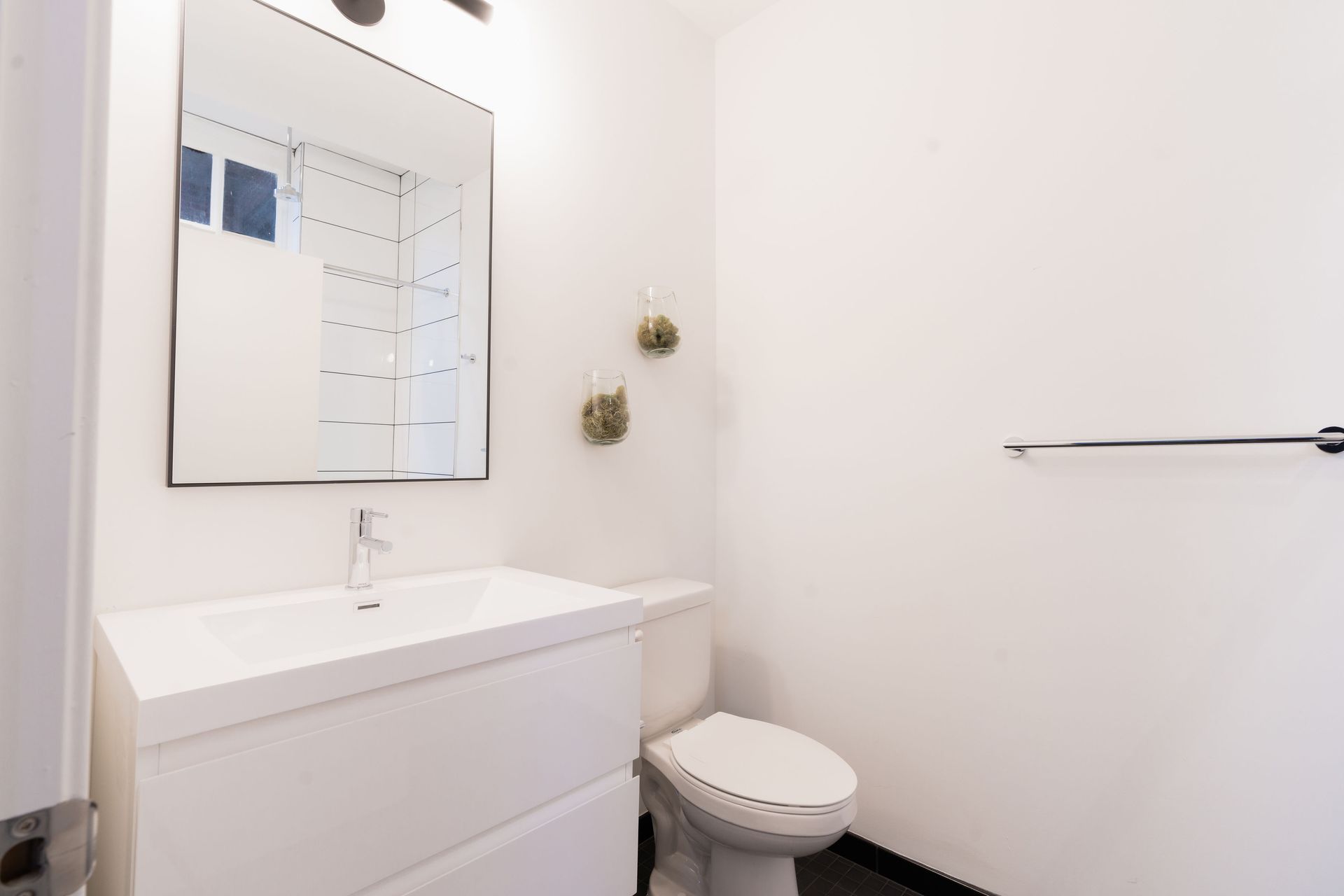 A bathroom with a toilet , sink and mirror.