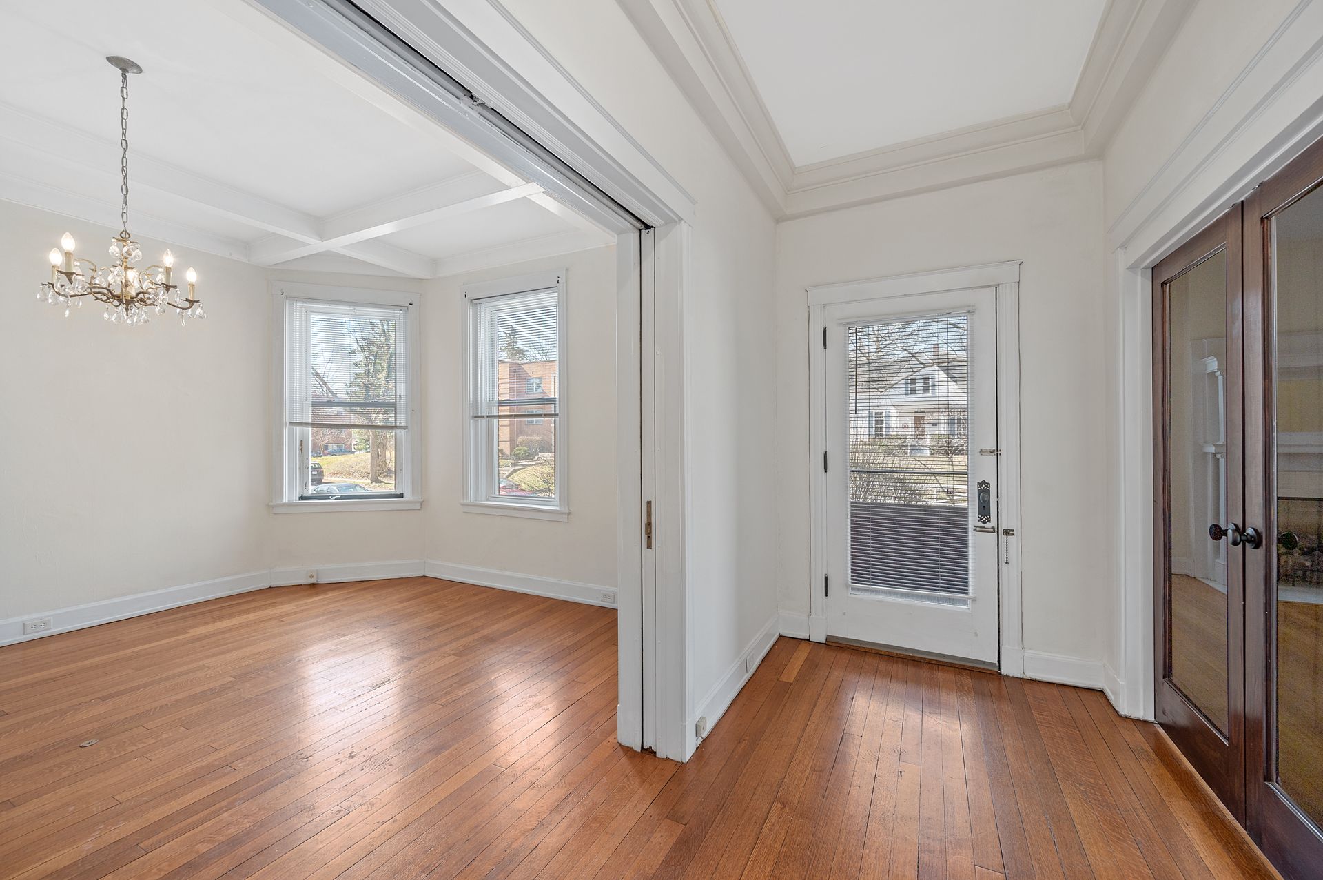 An empty room with hardwood floors and a chandelier