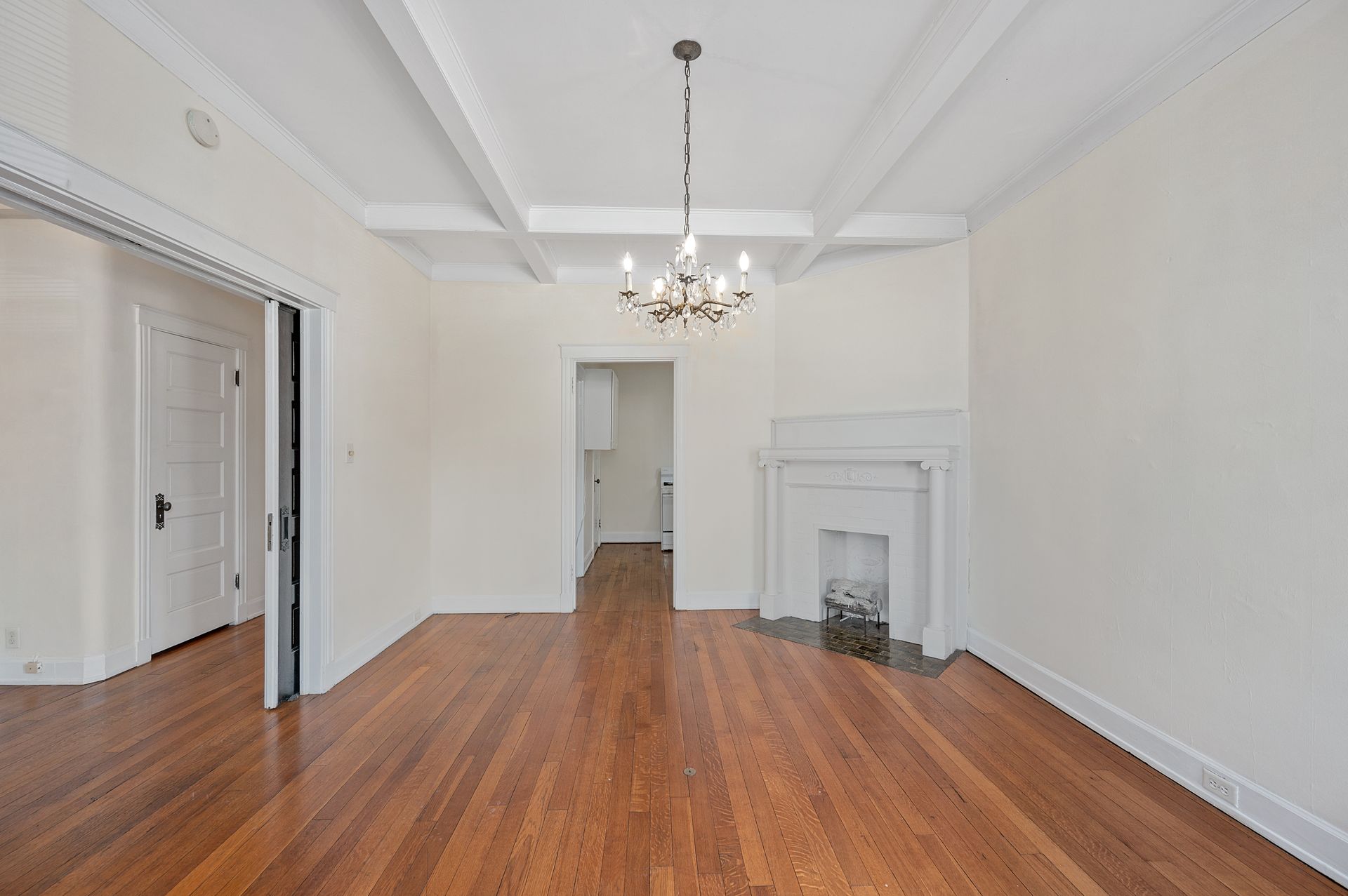 An empty living room with hardwood floors and a fireplace