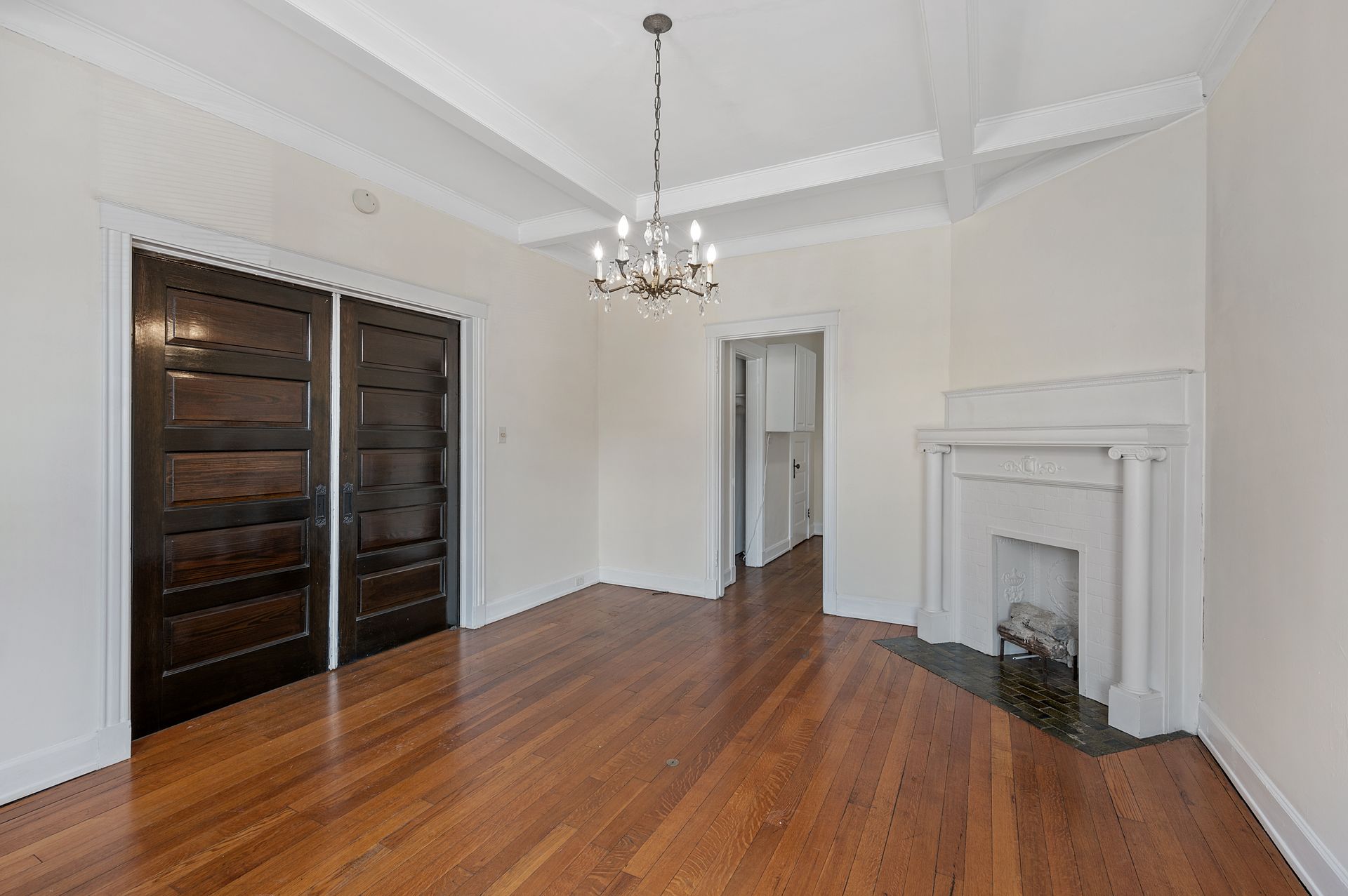 An empty living room with hardwood floors and a fireplace.