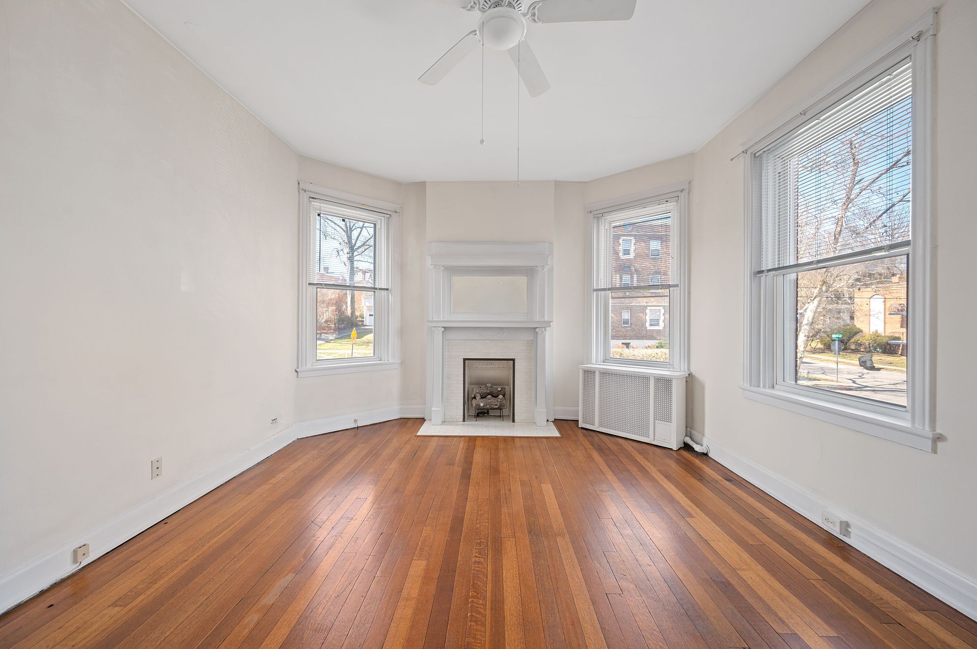 An empty living room with hardwood floors and a fireplace.
