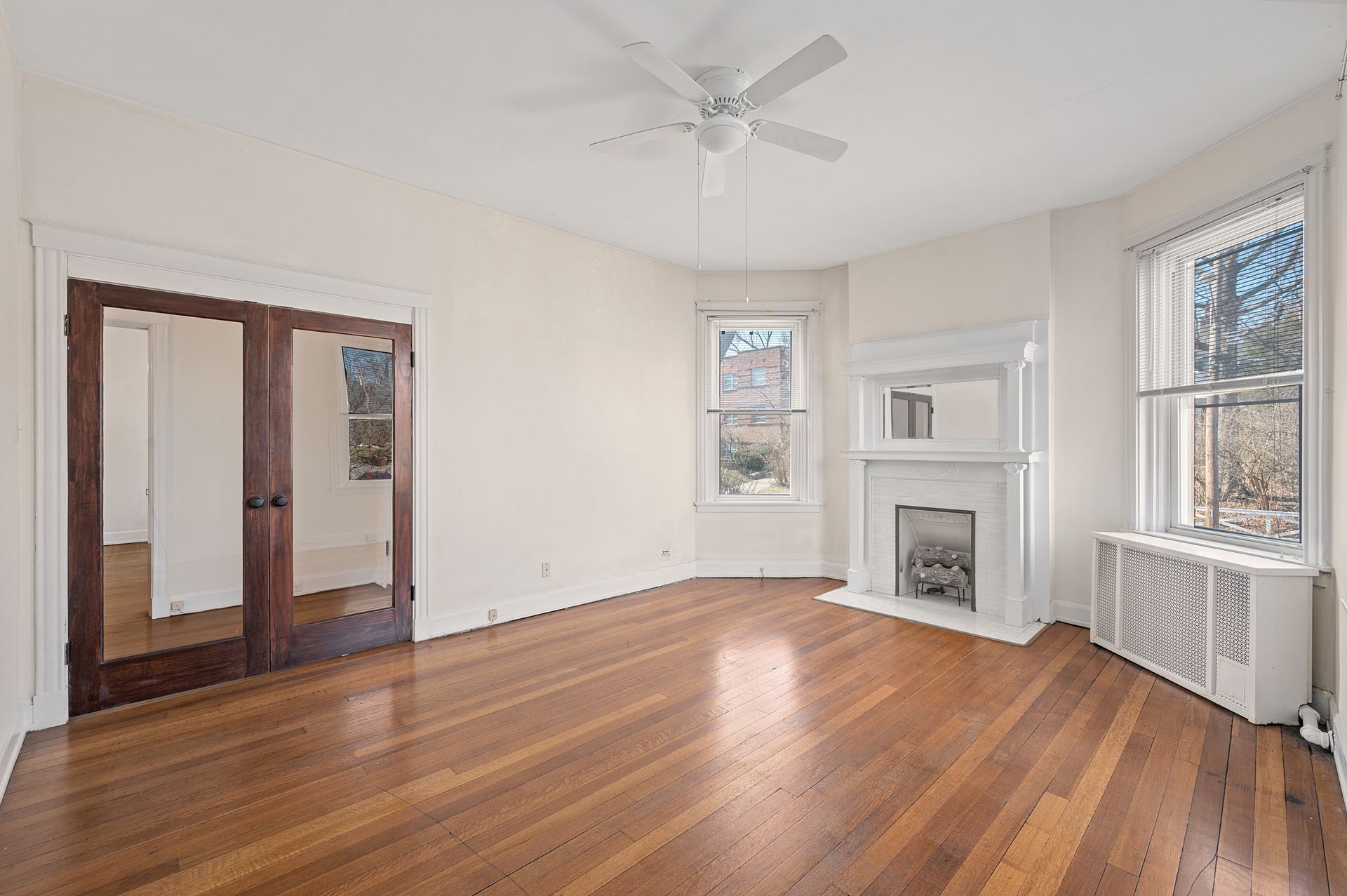 An empty living room with hardwood floors and a fireplace.