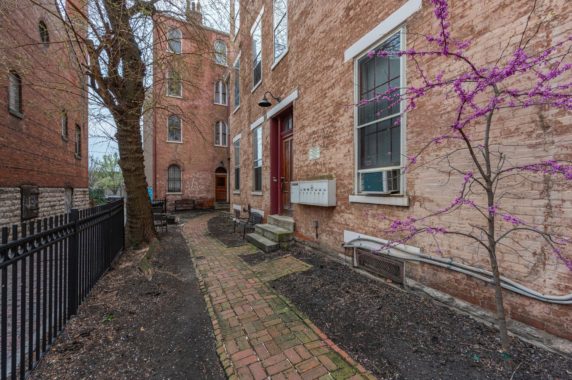 A brick building with a fence and a tree in front of it.