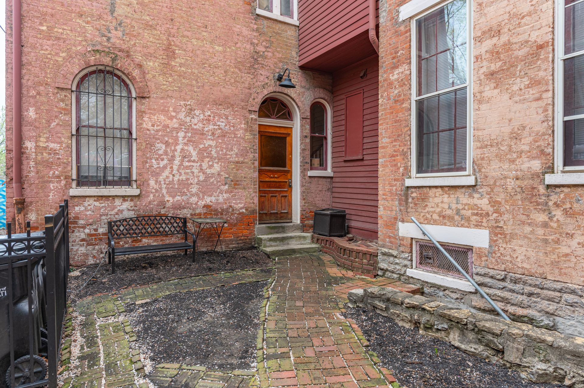 A brick building with a wooden door and a bench in front of it.