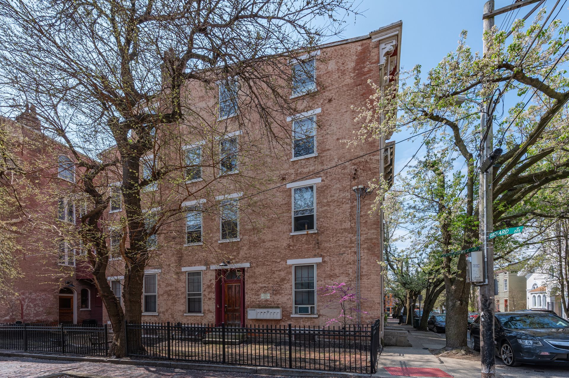 A brick building with a fence around it and trees in front of it.