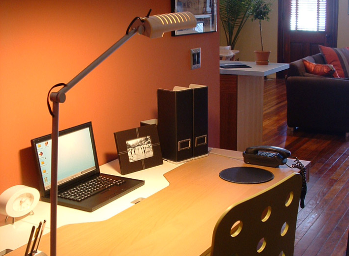 A desk with a laptop and a lamp on it