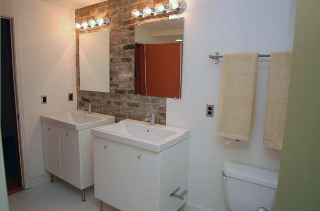 A bathroom with two sinks , a toilet and a mirror.