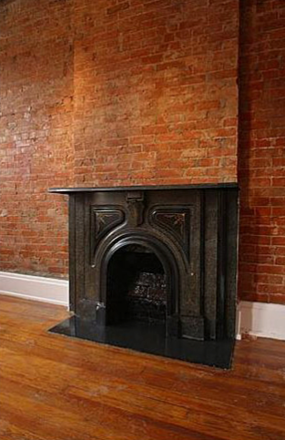 There is a fireplace in the middle of a room with a brick wall.