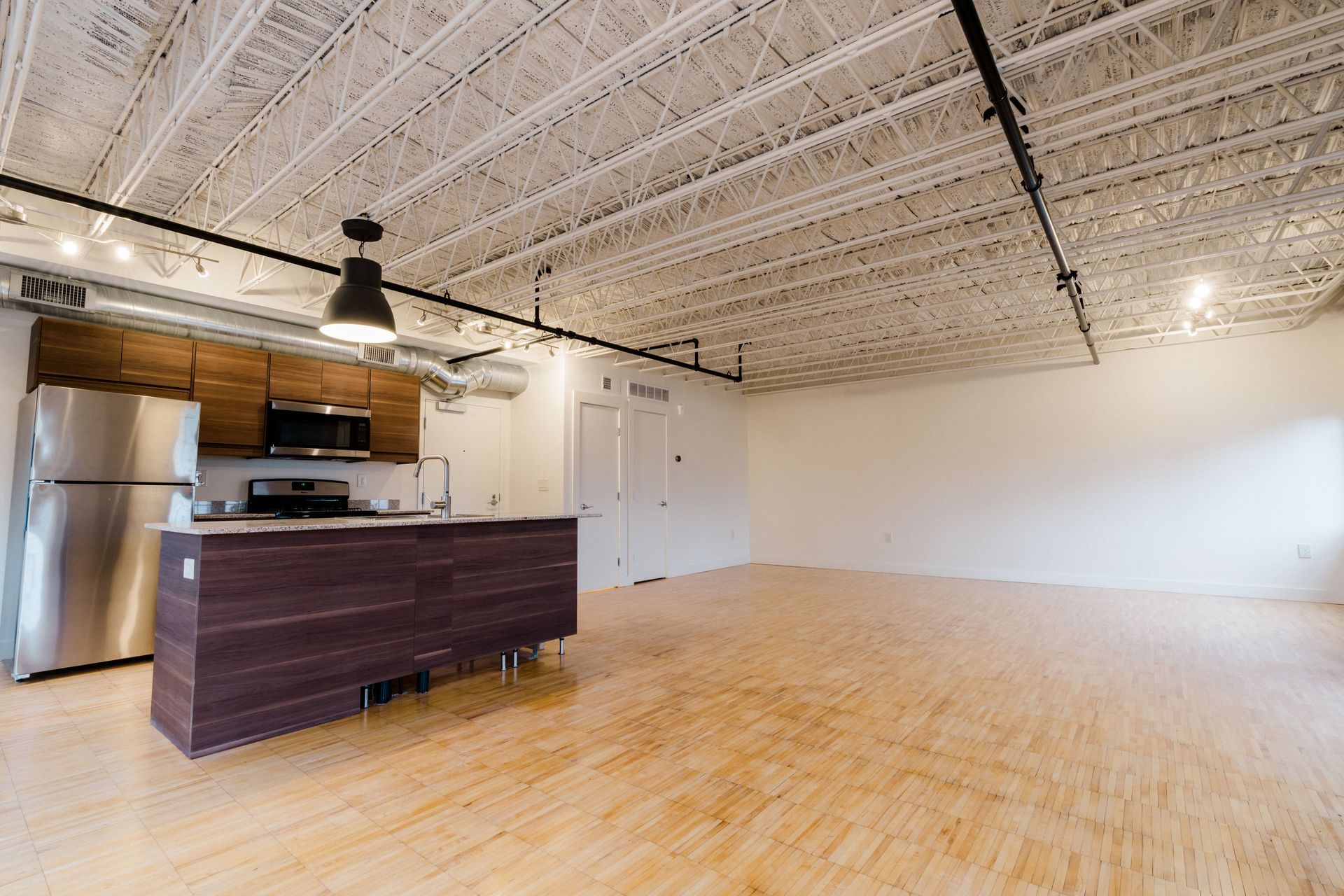 An empty kitchen with a stainless steel refrigerator and a wooden counter top.