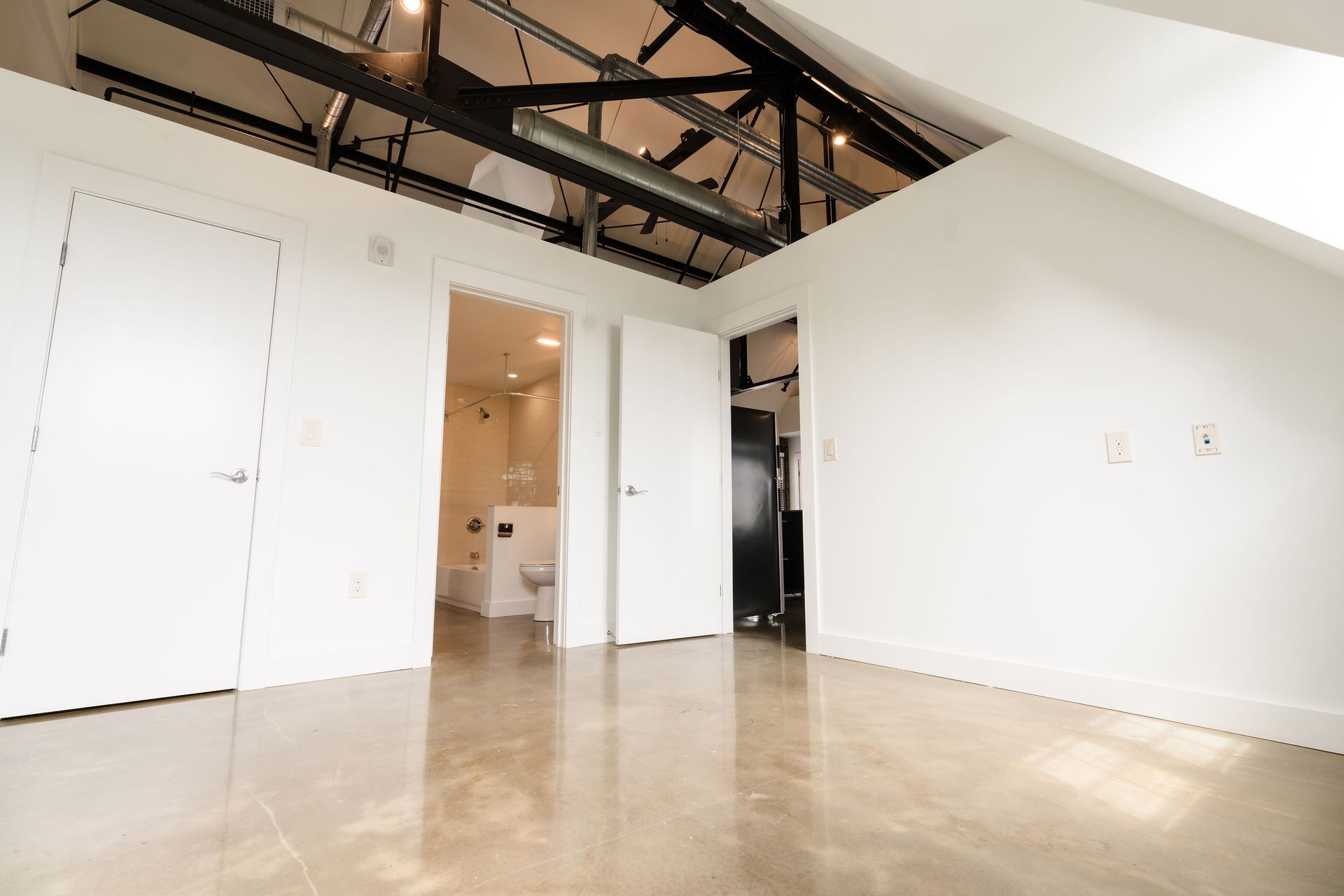 An empty room with white walls and a bathroom in the background