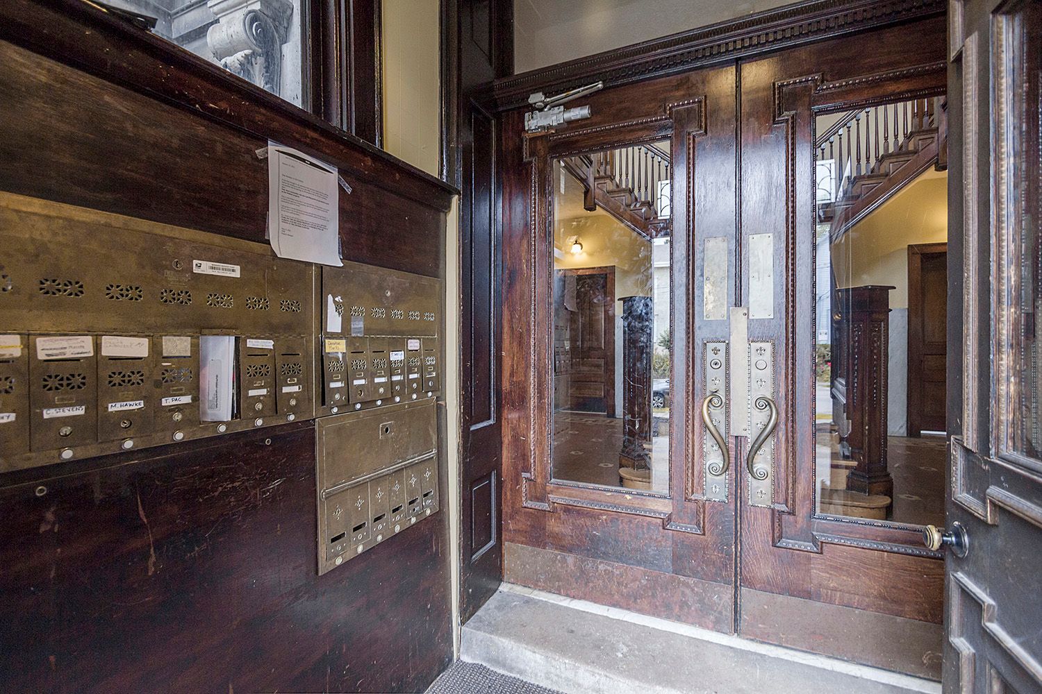 An entrance to a building with a wooden door and a mailbox.