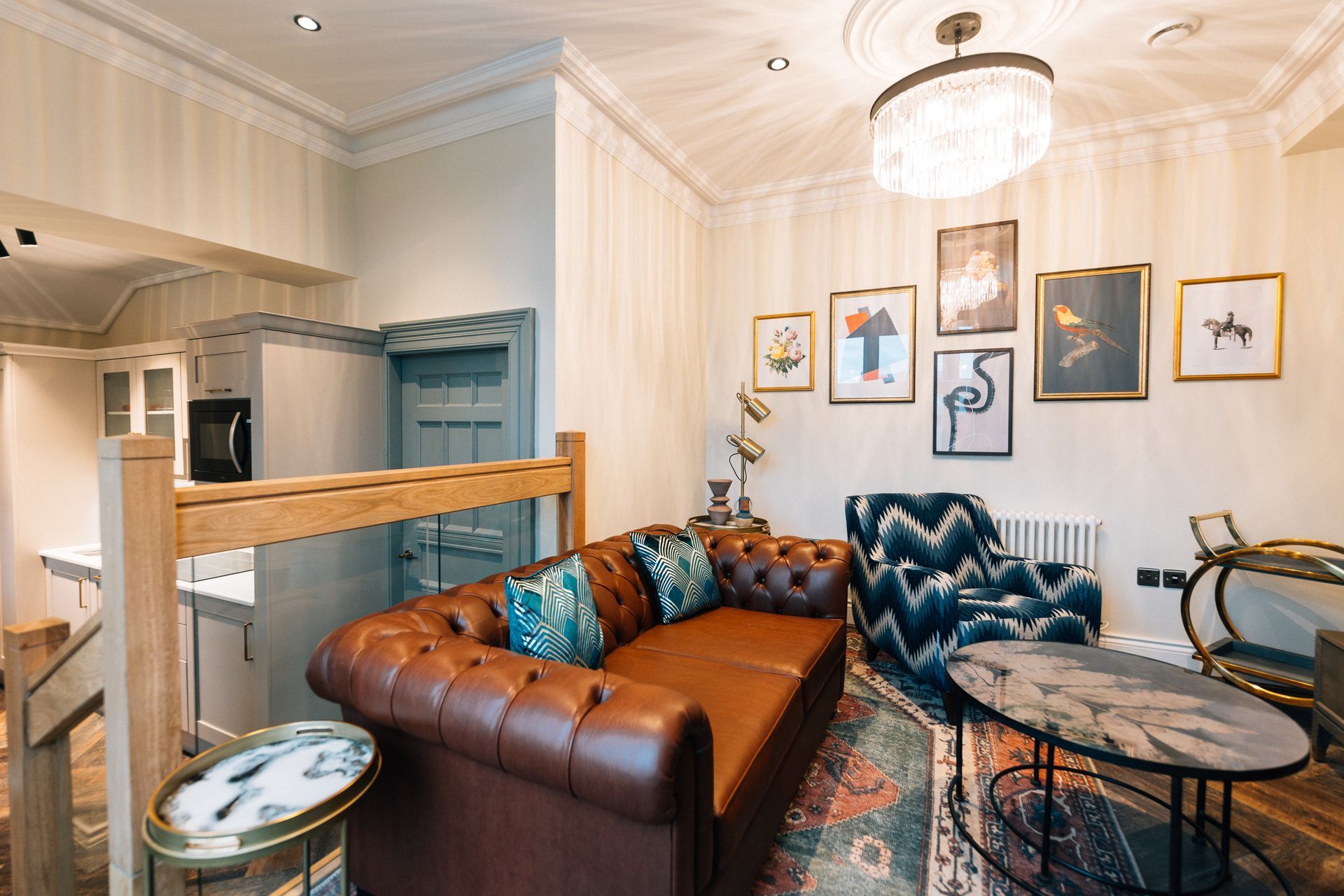 A cozy living room with a brown leather sofa, patterned armchair, and artwork on the wall.