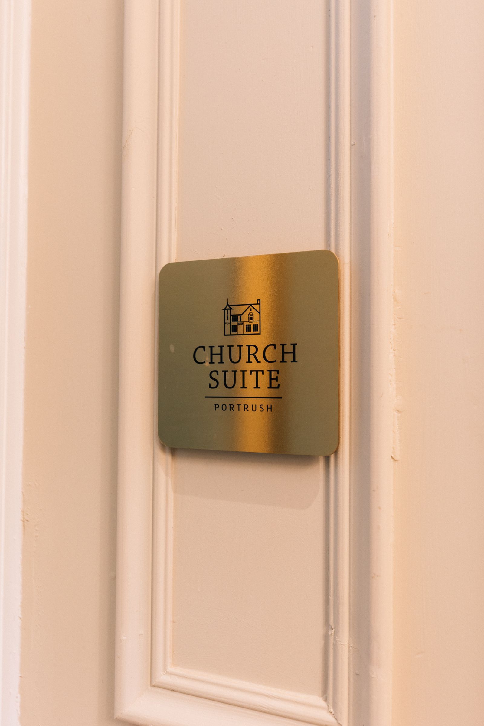 A brass sign on a white door indicates 