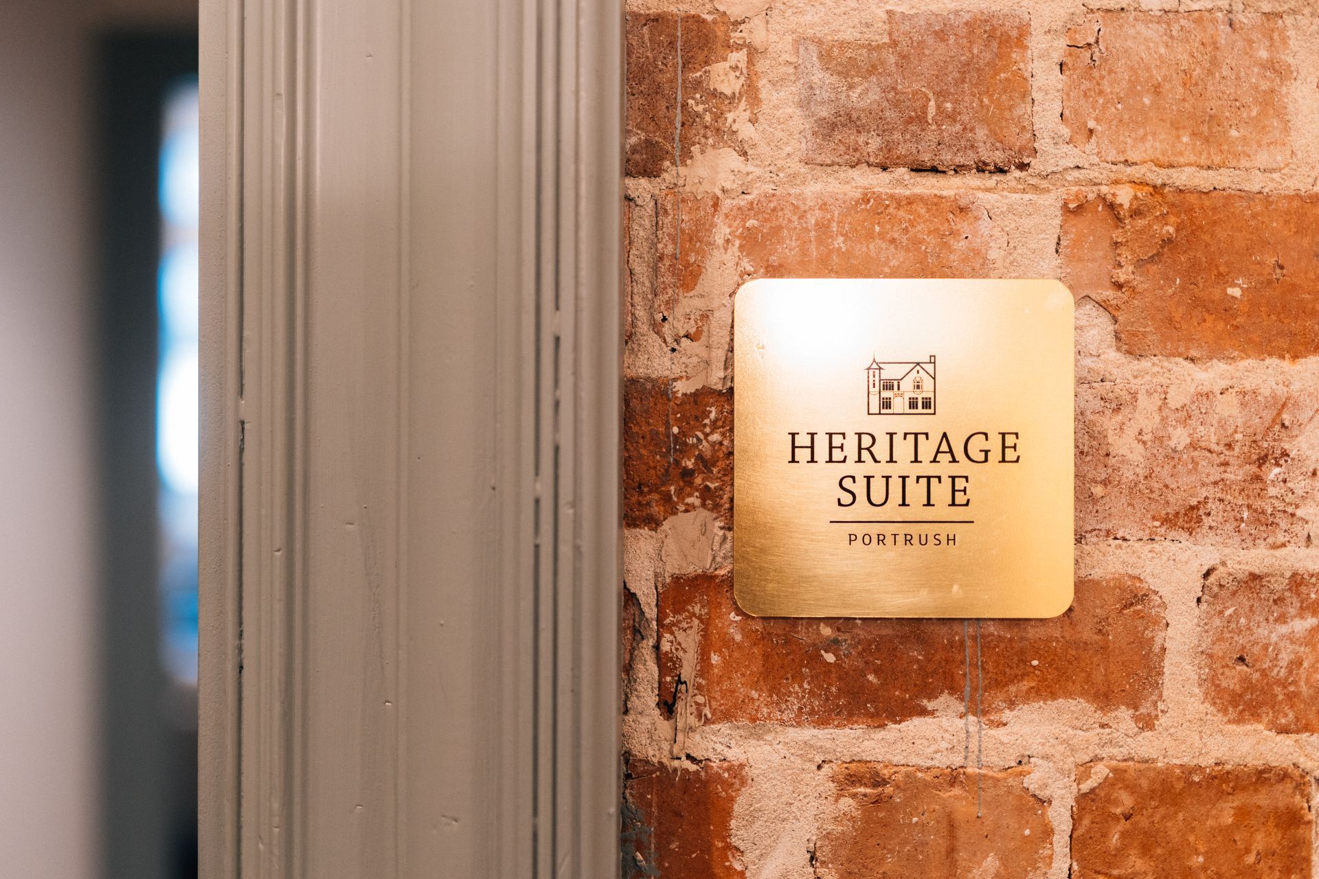 Gold “Heritage Suite” sign mounted on a brick wall beside a doorway