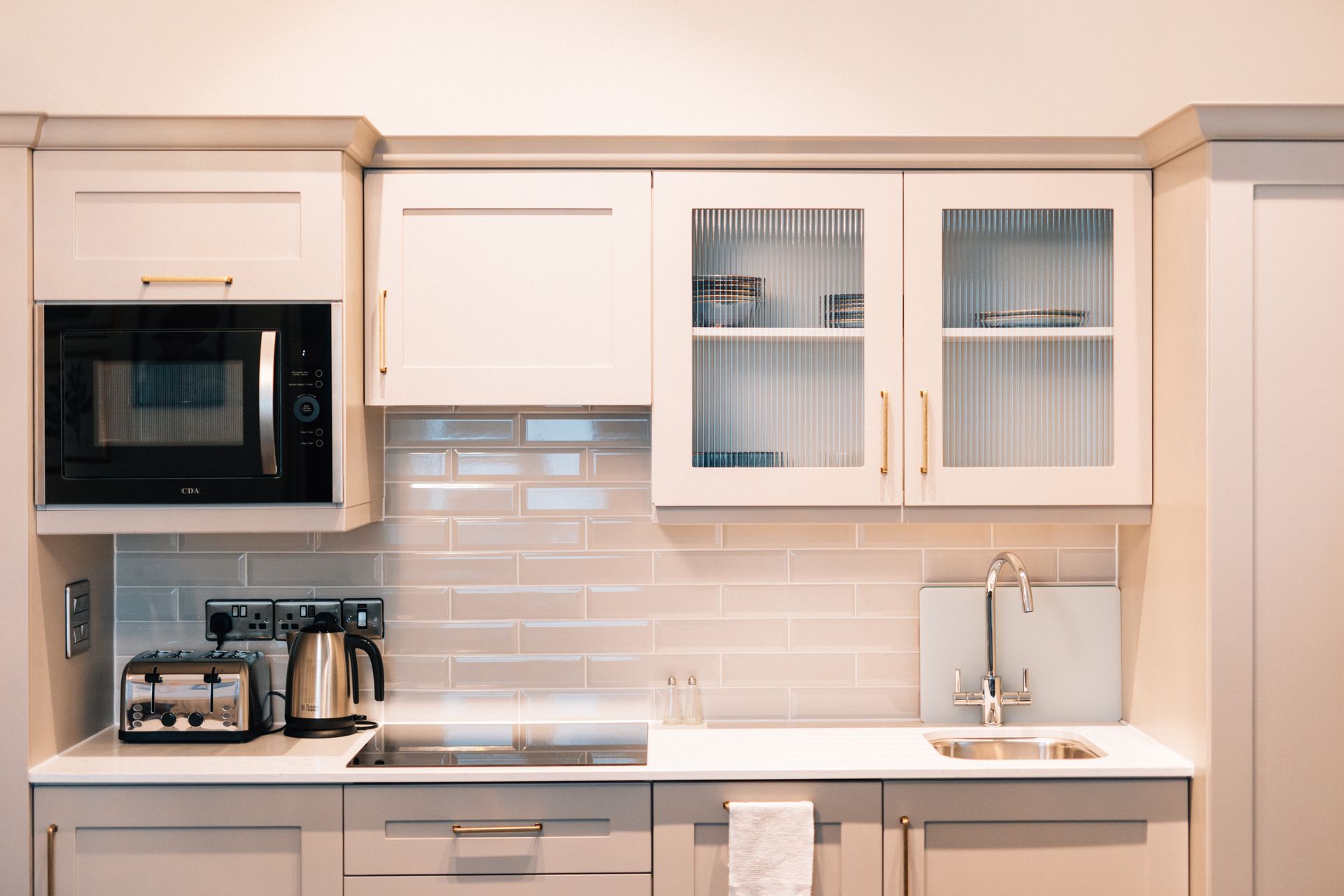 Small kitchen with light gray cabinets, a microwave, and a sink. 
