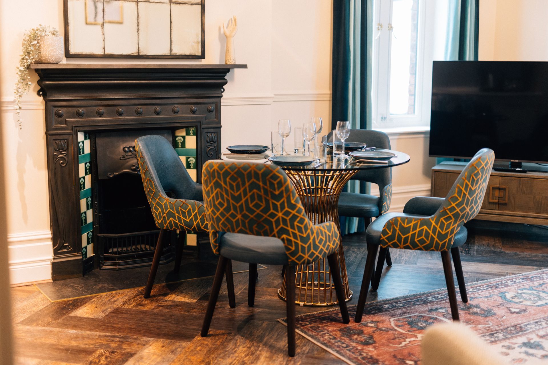 Living room with a round dining table and four patterned chairs, a fireplace, and a TV.