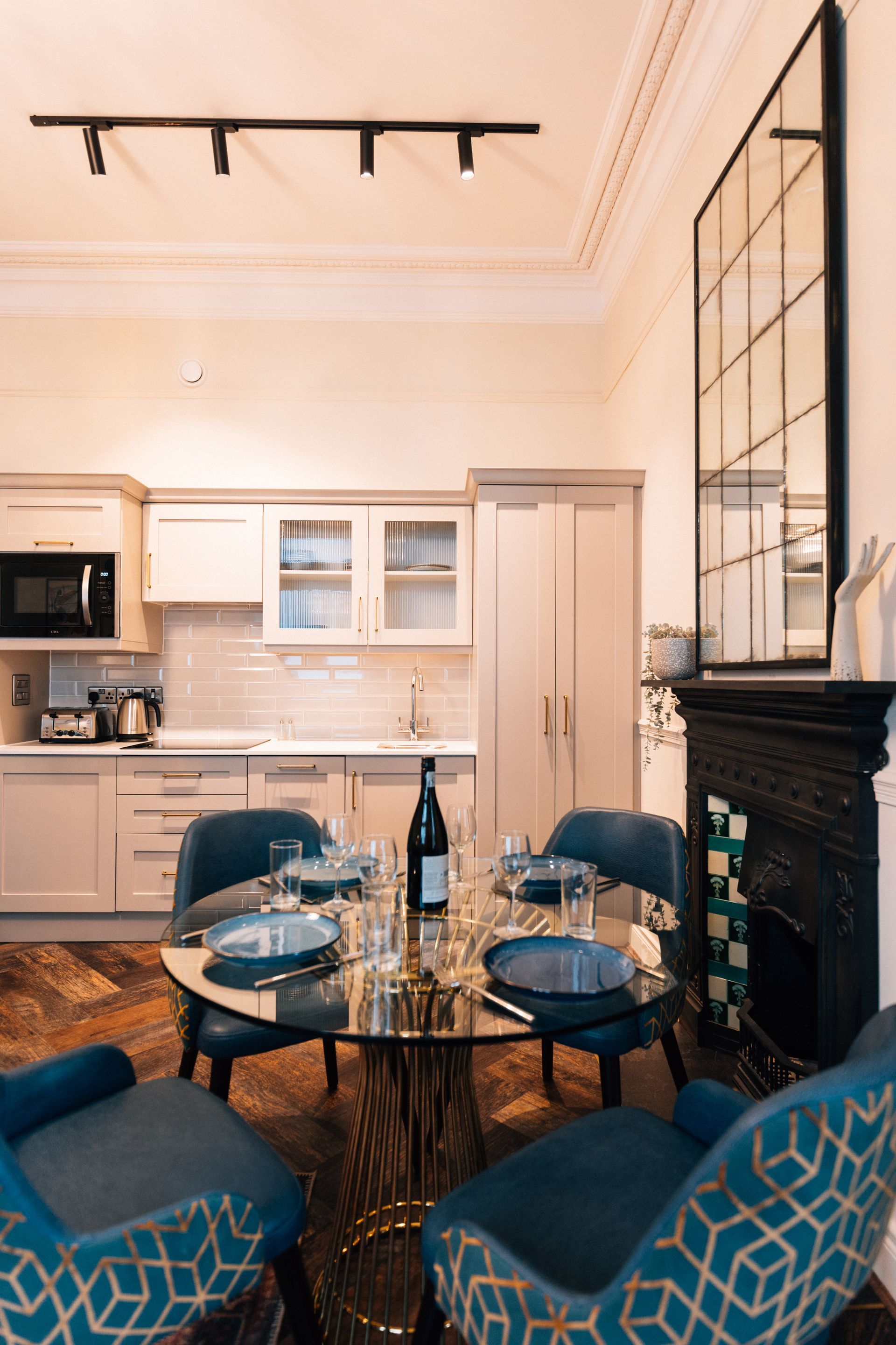 Dining area with a round glass table set for a meal, surrounded by blue chairs. 