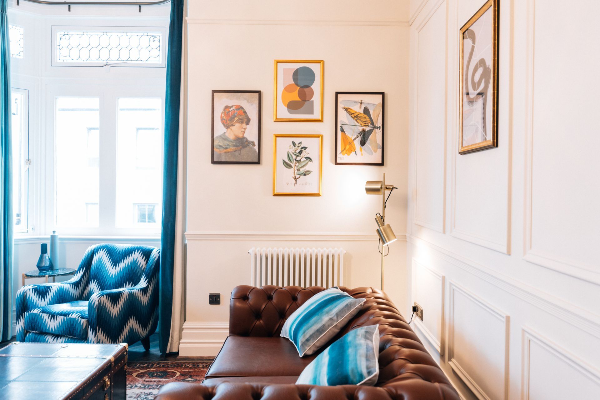 Living room with a brown leather sofa, framed art, and blue accents.