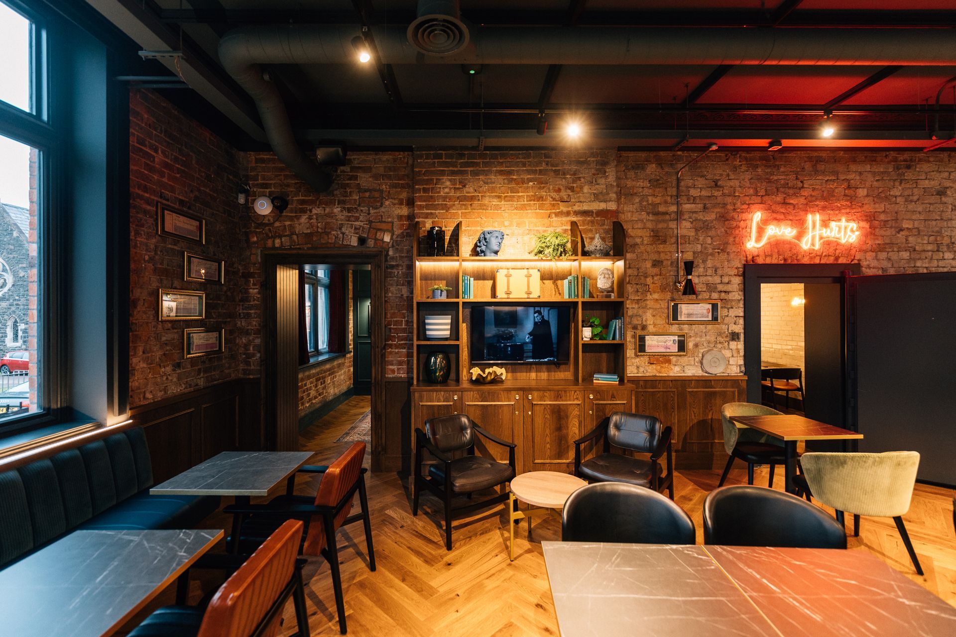 Interior of a cafe with brick walls, wood furniture, and a neon 