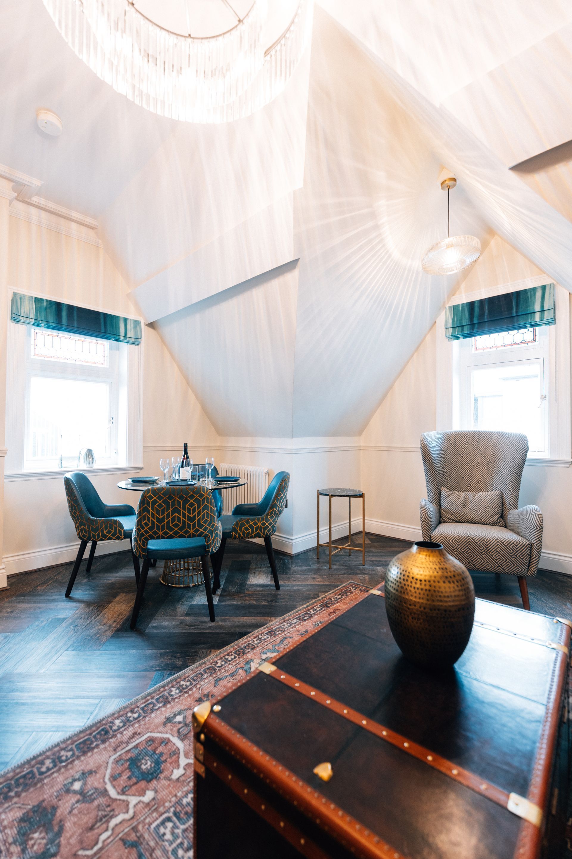 Attic room with dining table, ornate chairs, and antique trunk. 