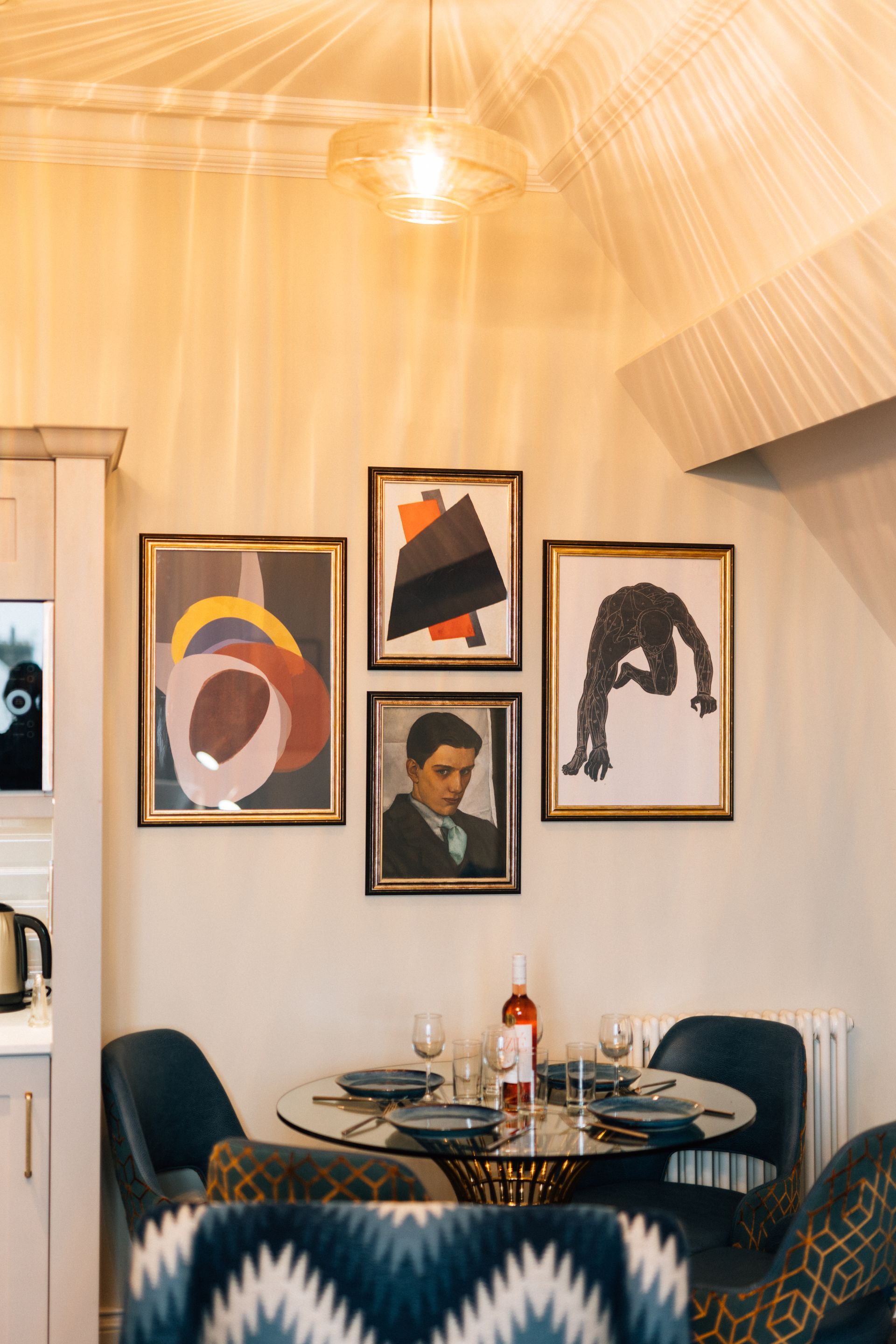Dining area with a round table set for a meal and a gallery wall of framed art.