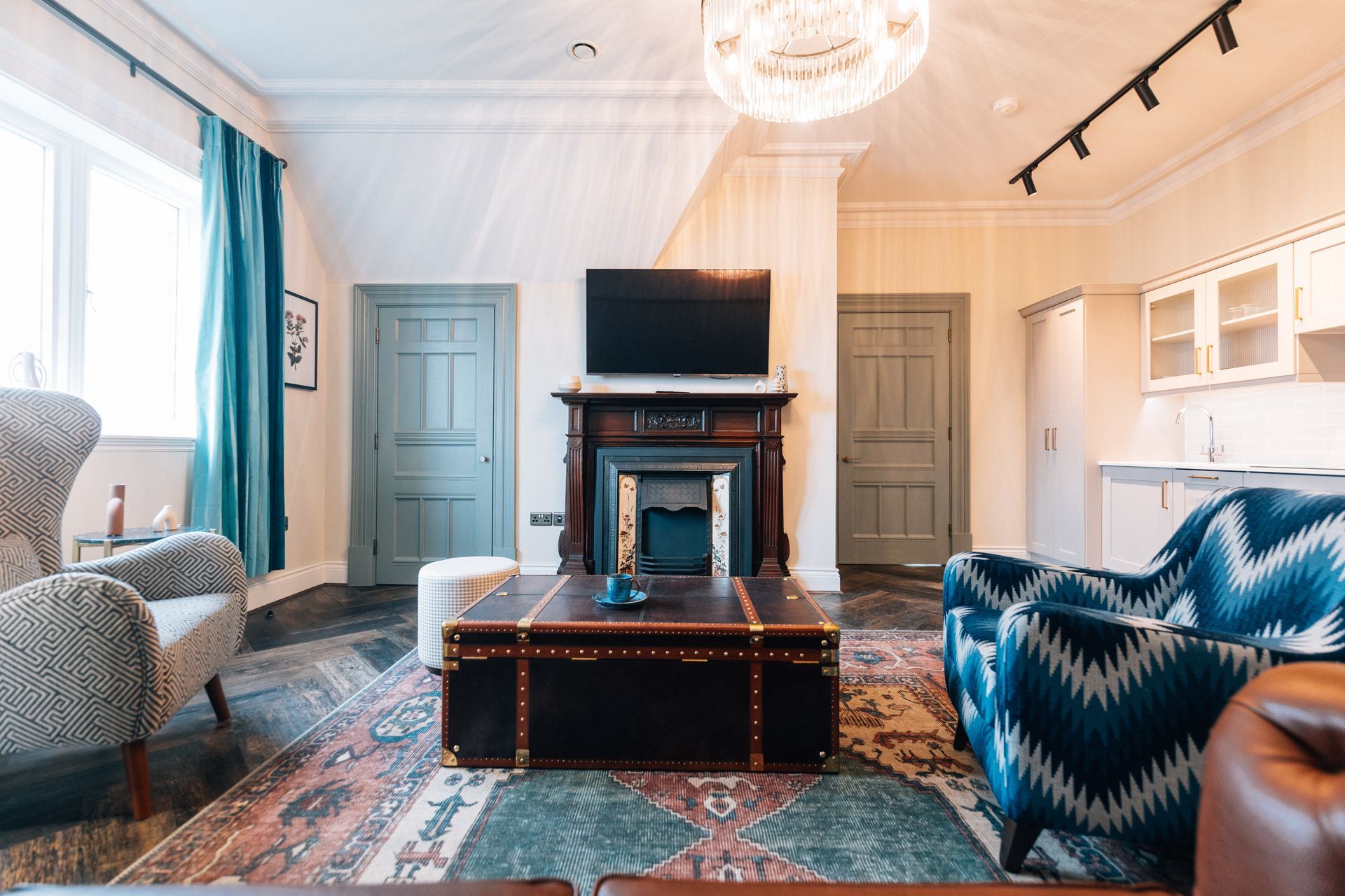 A cozy living room with a patterned rug, two armchairs, a fireplace, 