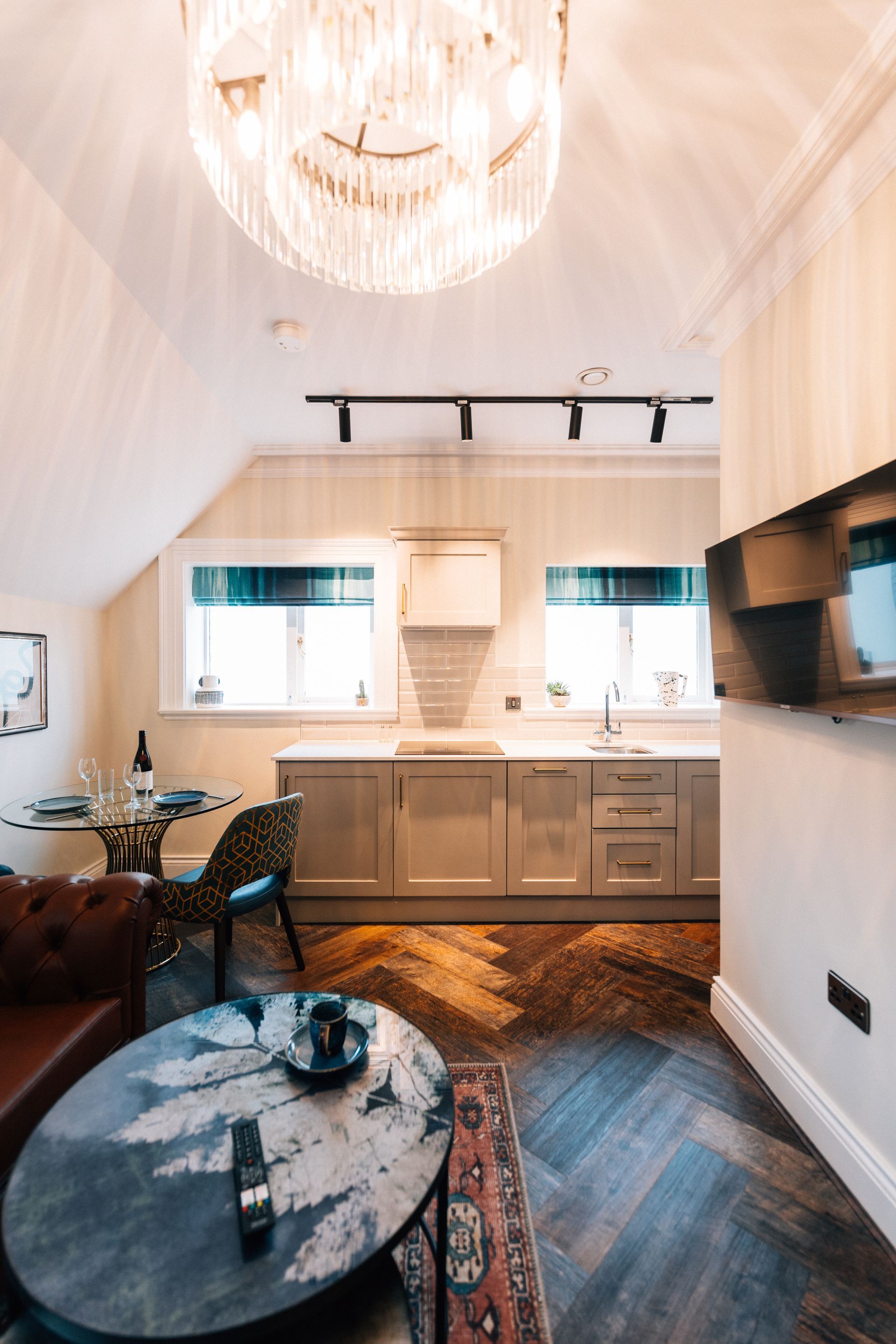 Cozy, modern kitchen and living space with herringbone floors. Includes a table, seating area