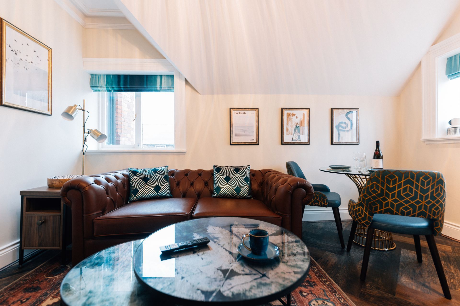 Cozy living room with a brown leather sofa, a glass coffee table, and artwork on the walls