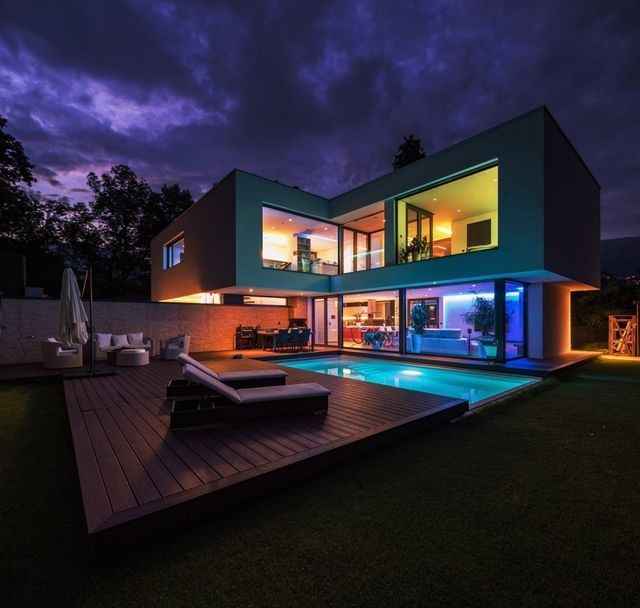A Modern House With A Swimming Pool In The Backyard At Night — NFL Electrical In Wamuran, QLD