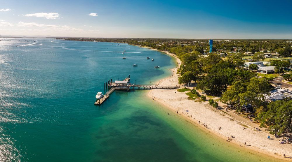 An Aerial View Of A Beach With A Pier In The Water — NFL Electrical In Baringa, QLD