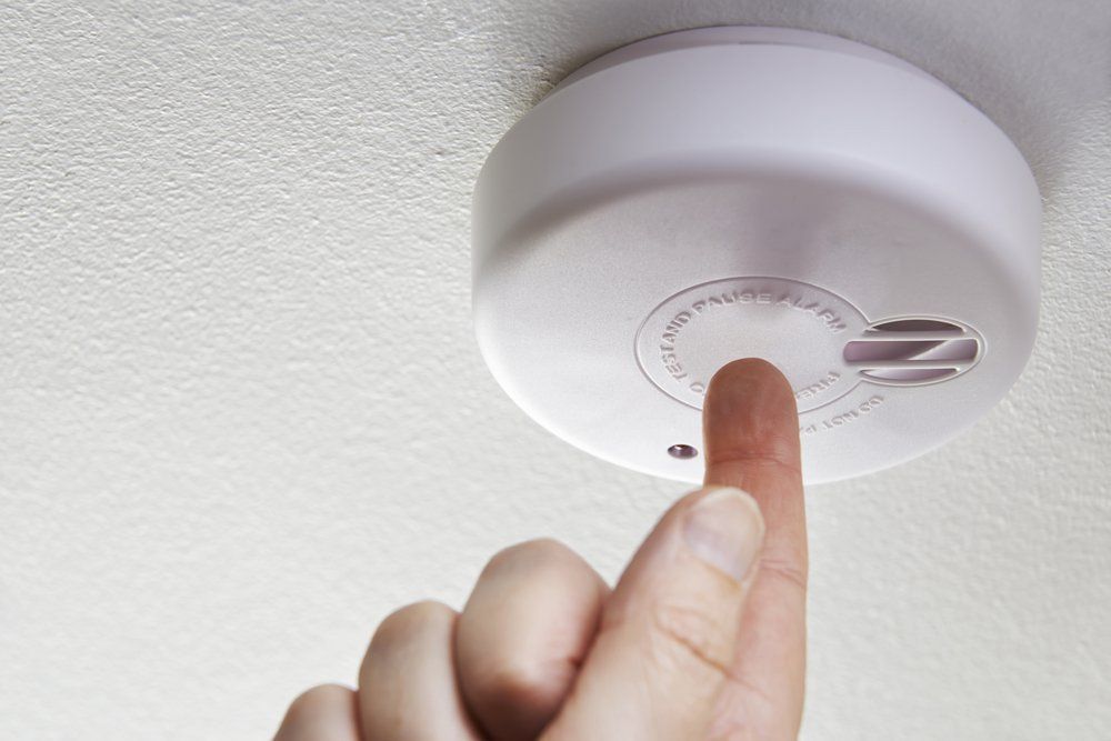 A Person Is Pointing At A Smoke Detector On The Ceiling — NFL Electrical In Baringa, QLD