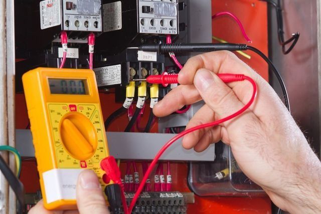 A Person Is Using A Digital Multimeter To Test A Circuit Board — NFL Electrical In Wamuran, QLD