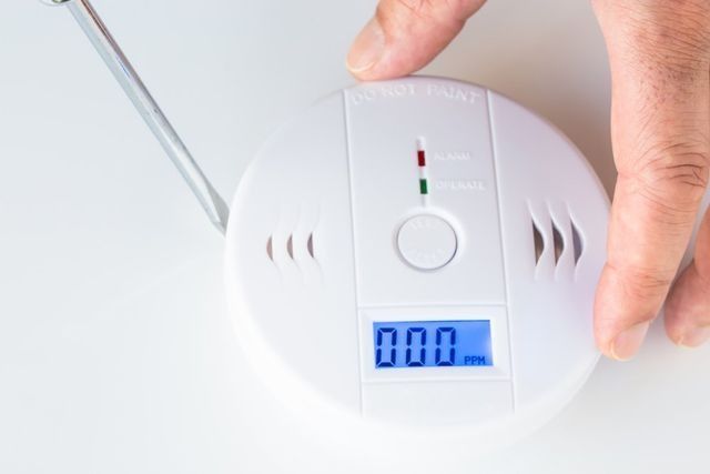 A Person Is Holding A Smoke Detector With A Screwdriver — NFL Electrical In Wamuran, QLD