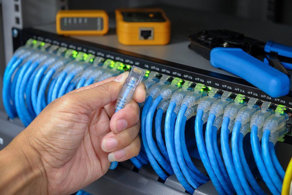 A Person Is Holding A Wire In Their Hand In Front Of A Bunch Of Wires — NFL Electrical In Winya, QLD