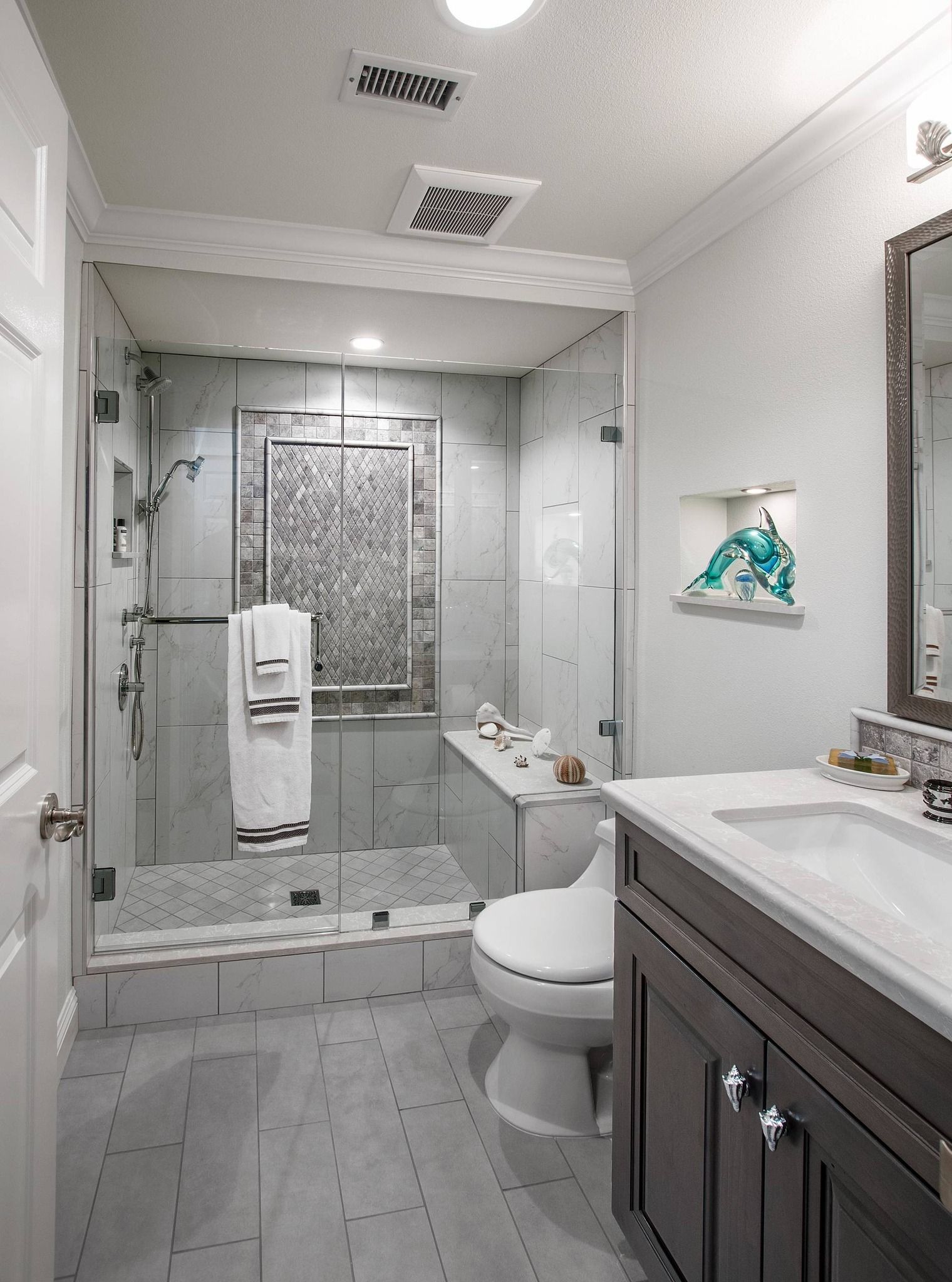 Bathroom with a glass shower, gray tiles, a dark vanity, and a toilet.